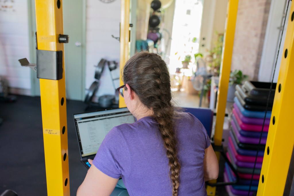 trainer working on client programs on a laptop